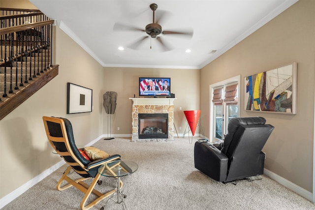 living area featuring carpet flooring, a stone fireplace, ceiling fan, and crown molding