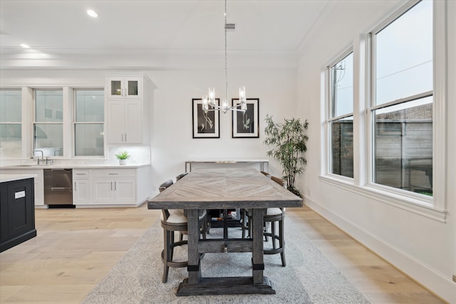 dining room featuring a chandelier, sink, light hardwood / wood-style floors, and crown molding