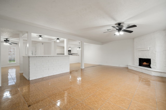 unfurnished living room with ceiling fan, a fireplace, and a textured ceiling