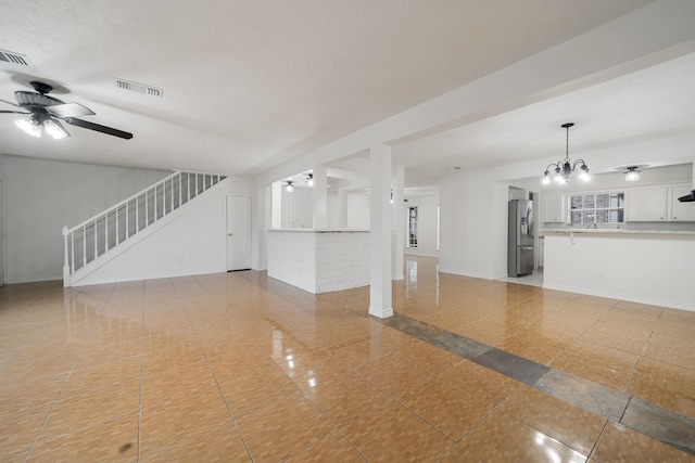 unfurnished living room with ceiling fan with notable chandelier, light tile patterned flooring, and sink