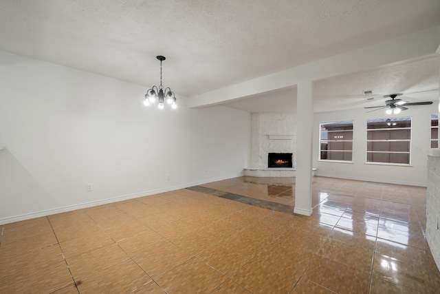 unfurnished living room with tile patterned floors, a fireplace, ceiling fan with notable chandelier, and a textured ceiling