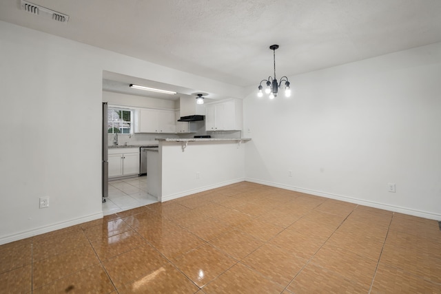 kitchen with kitchen peninsula, a breakfast bar, white cabinets, a chandelier, and hanging light fixtures