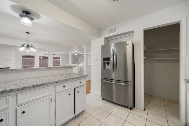 kitchen featuring an inviting chandelier, white cabinets, stainless steel refrigerator with ice dispenser, light stone countertops, and light tile patterned floors