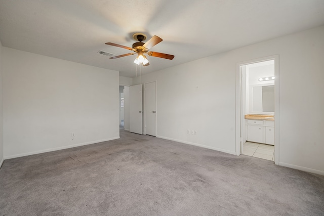 unfurnished bedroom with light colored carpet, ensuite bath, and ceiling fan