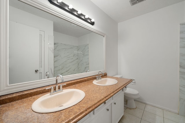 bathroom with toilet, vanity, and tile patterned floors