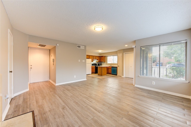 unfurnished living room with plenty of natural light, light hardwood / wood-style flooring, and a textured ceiling