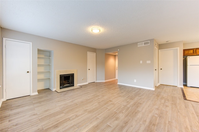 unfurnished living room featuring a textured ceiling and light hardwood / wood-style flooring