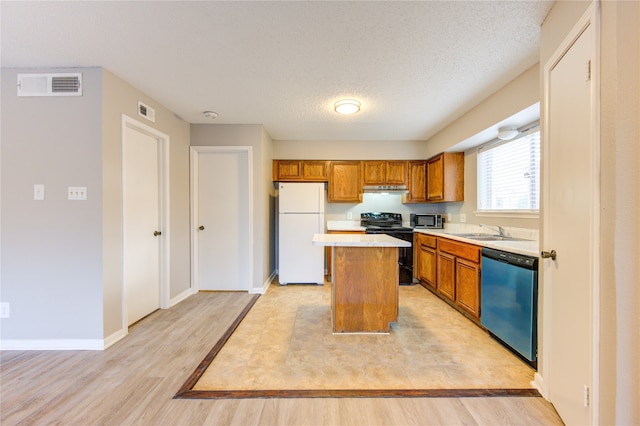 kitchen featuring light hardwood / wood-style flooring, a textured ceiling, sink, a kitchen island, and appliances with stainless steel finishes