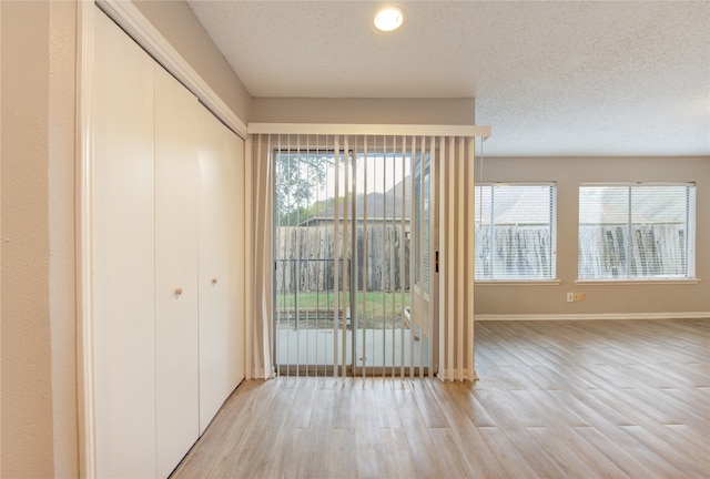 interior space with a wealth of natural light, a textured ceiling, and light hardwood / wood-style flooring