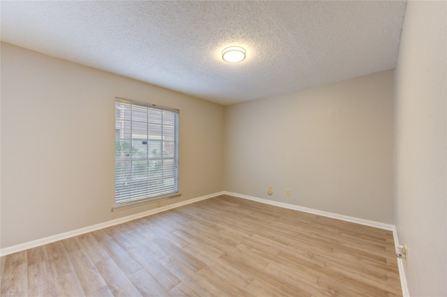 spare room with a textured ceiling and light hardwood / wood-style floors