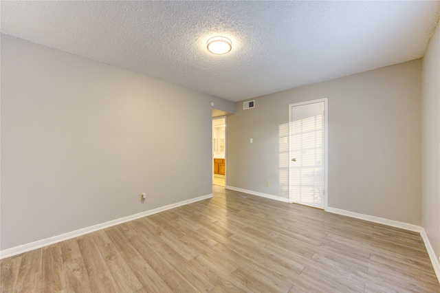 empty room featuring light hardwood / wood-style floors and a textured ceiling