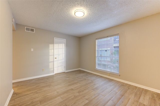 spare room with a textured ceiling and light hardwood / wood-style floors