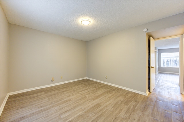 spare room with light hardwood / wood-style floors and a textured ceiling