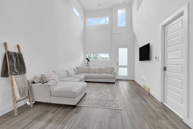 living room with a high ceiling and light wood-type flooring