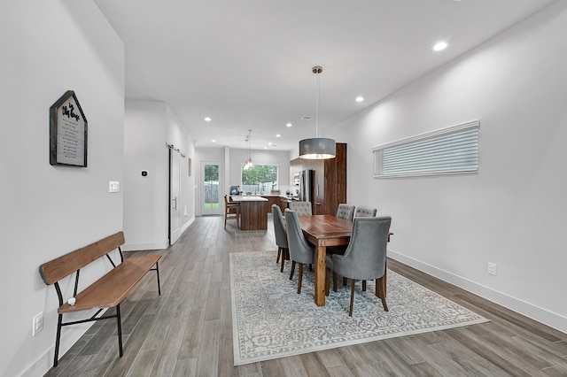 dining space with a barn door and wood-type flooring