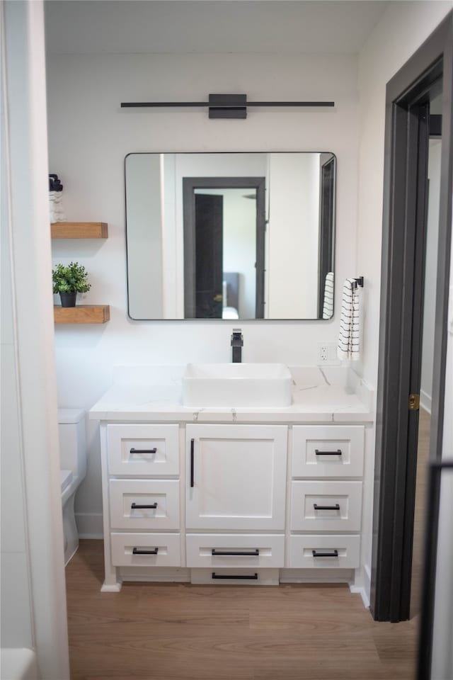 bathroom with hardwood / wood-style flooring, vanity, and toilet