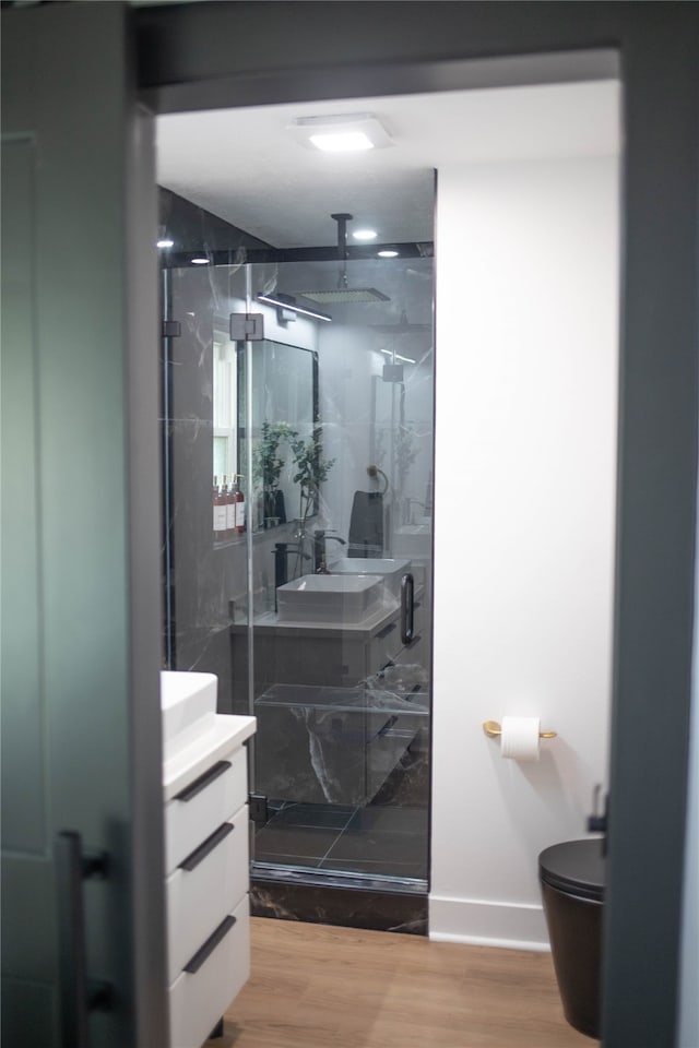 bathroom featuring walk in shower, wood-type flooring, vanity, and toilet