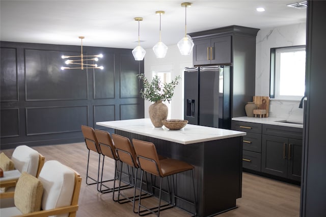 kitchen featuring wood-type flooring, a center island, stainless steel fridge, gray cabinetry, and pendant lighting