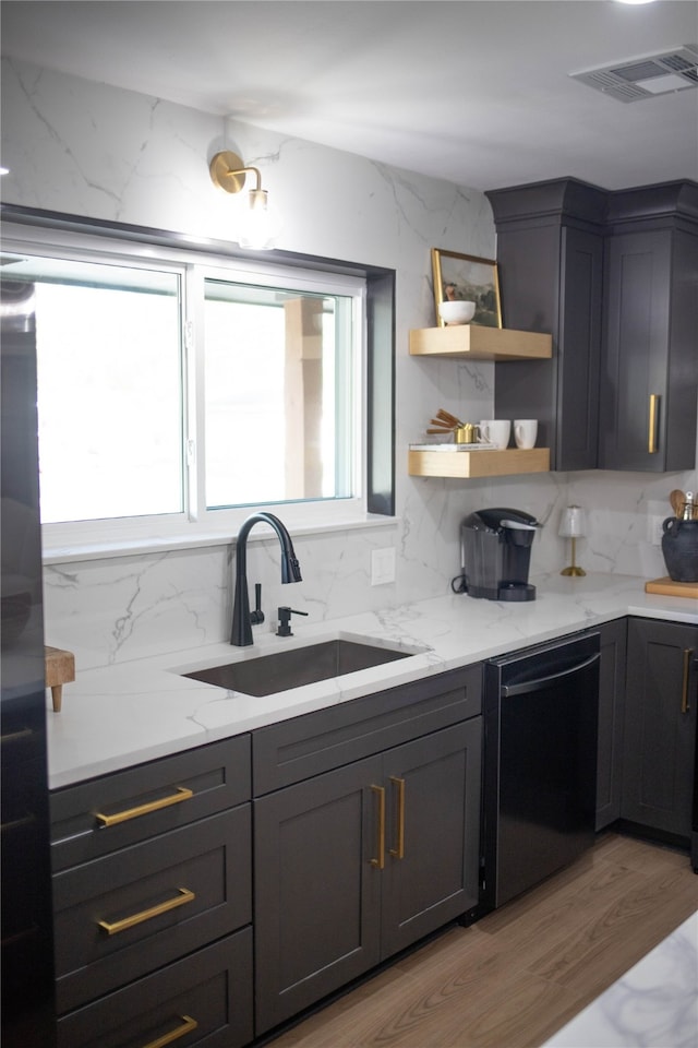 kitchen with light stone counters, decorative backsplash, sink, dishwasher, and light hardwood / wood-style flooring