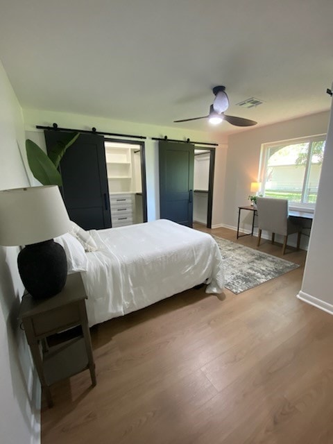 bedroom featuring a barn door, hardwood / wood-style flooring, and ceiling fan