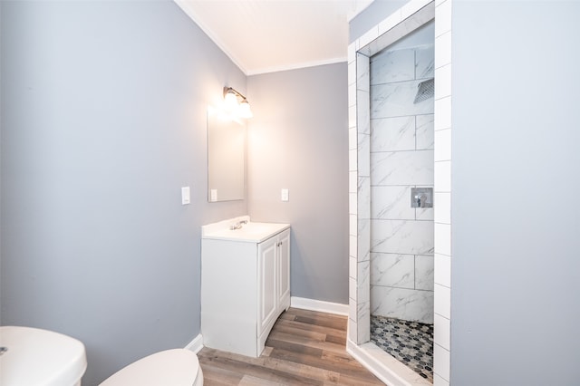 bathroom featuring crown molding, a tile shower, wood-type flooring, and toilet