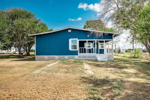 back of property with a yard and a porch