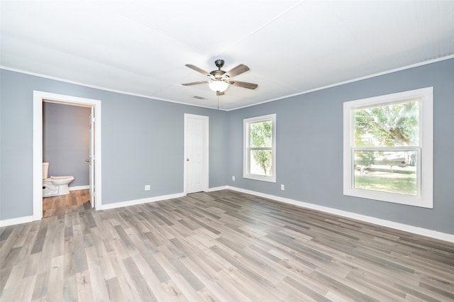 unfurnished bedroom featuring ceiling fan, ensuite bath, light wood-type flooring, and crown molding