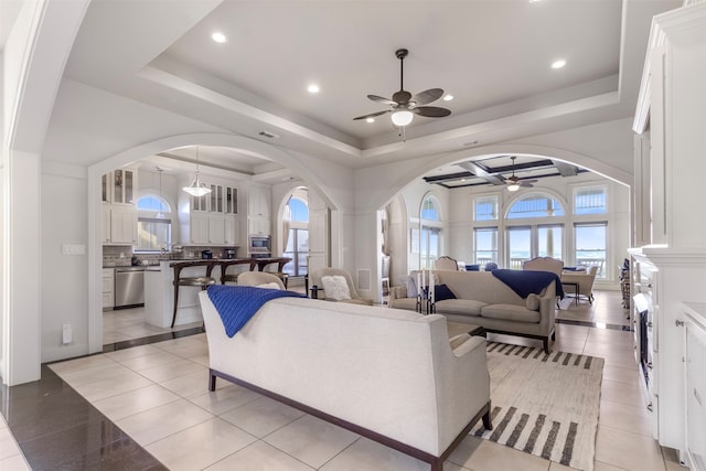 living room with ceiling fan, a raised ceiling, and light tile patterned floors