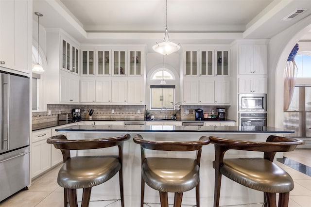 kitchen featuring stainless steel appliances, white cabinetry, light tile patterned floors, pendant lighting, and a breakfast bar area