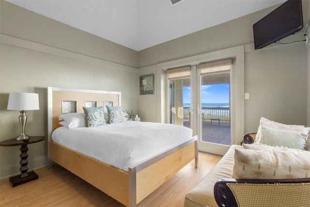 bedroom featuring access to outside, a water view, and light hardwood / wood-style floors