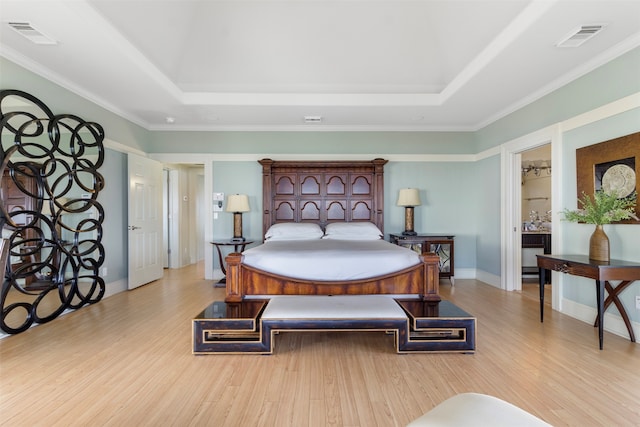 bedroom featuring a raised ceiling, light wood-type flooring, and crown molding