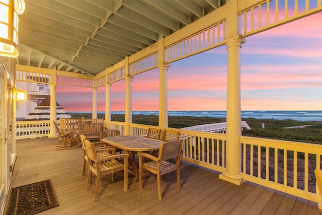 deck at dusk with a water view and a beach view