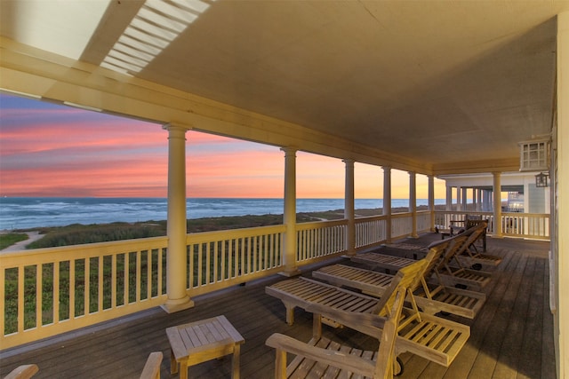 deck at dusk with a water view and a beach view