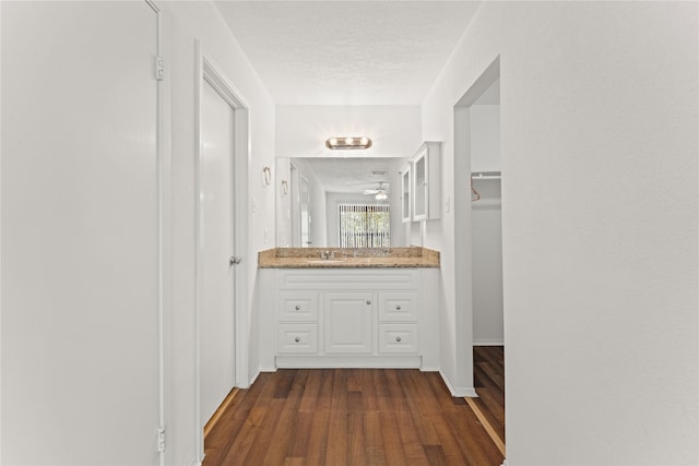 corridor with a textured ceiling, sink, and dark hardwood / wood-style flooring