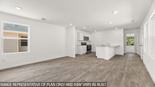 kitchen with white cabinets, light hardwood / wood-style flooring, sink, light stone countertops, and appliances with stainless steel finishes