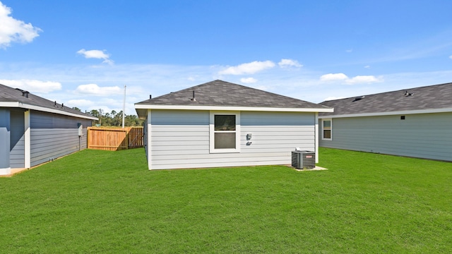 rear view of property featuring central air condition unit and a yard