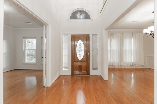 foyer with light hardwood / wood-style flooring, a chandelier, and crown molding