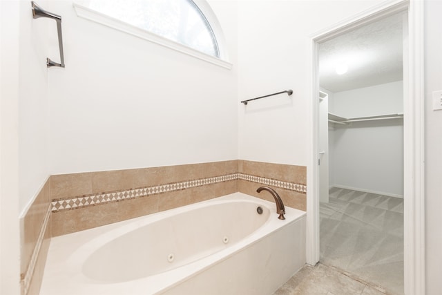 bathroom with a bathtub, a textured ceiling, and tile patterned flooring