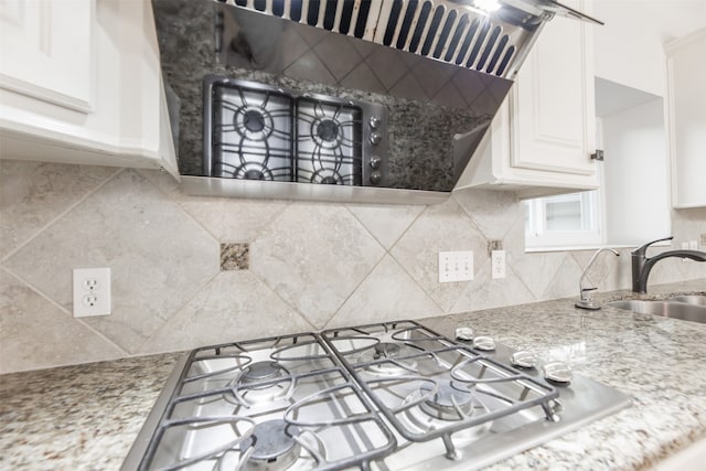 kitchen with light stone countertops, decorative backsplash, sink, white cabinets, and stainless steel gas cooktop