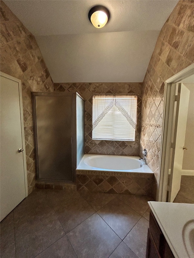 bathroom with tile walls, tile patterned flooring, and vaulted ceiling