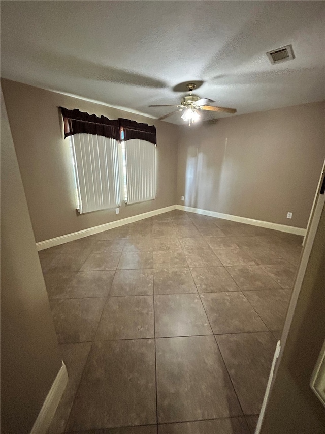 tiled empty room featuring ceiling fan and a textured ceiling