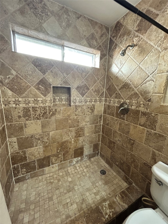 bathroom featuring a tile shower and toilet