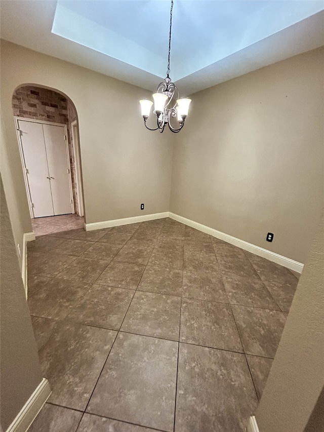 unfurnished dining area with dark tile patterned flooring and a notable chandelier