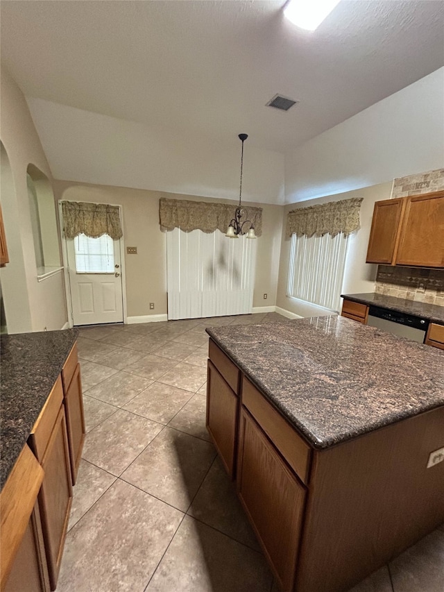 kitchen with hanging light fixtures, light tile patterned floors, tasteful backsplash, a kitchen island, and a chandelier