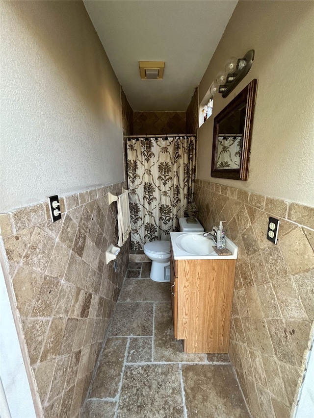 bathroom featuring curtained shower, vanity, tile walls, and toilet