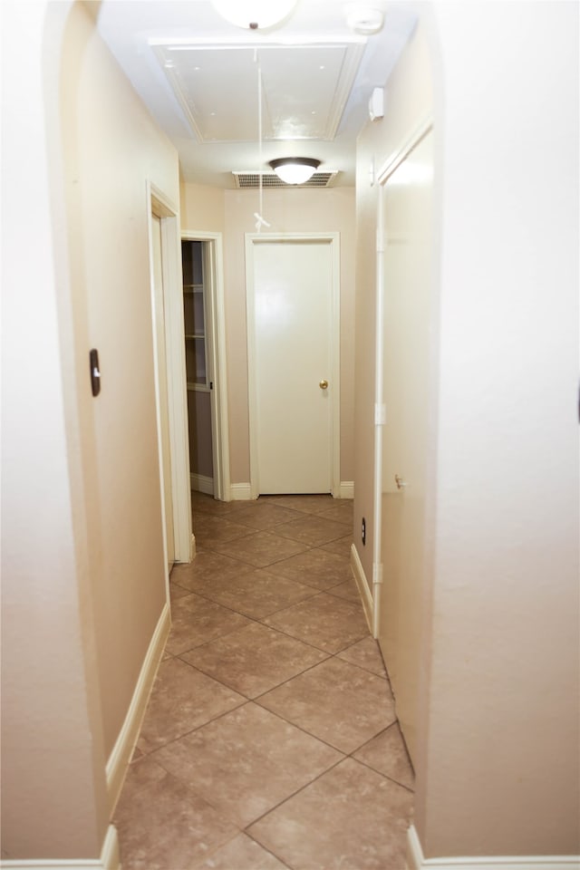 hall with a raised ceiling and light tile patterned floors