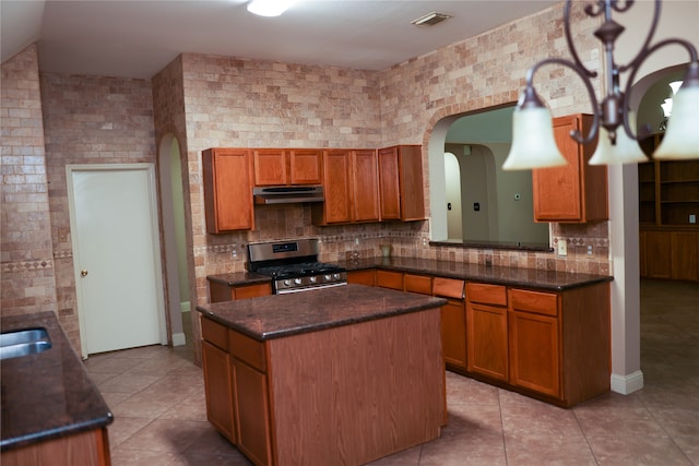 kitchen with tasteful backsplash, stainless steel gas range oven, a center island, and light tile patterned flooring