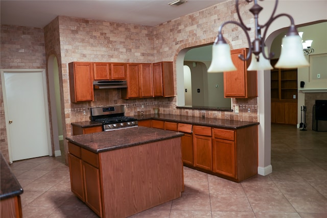 kitchen with decorative backsplash, a center island, stainless steel range with gas cooktop, and light tile patterned floors