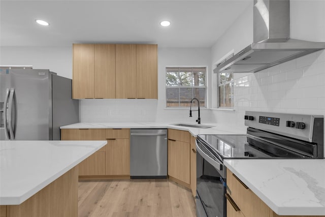 kitchen featuring sink, light hardwood / wood-style flooring, wall chimney exhaust hood, light brown cabinetry, and stainless steel appliances