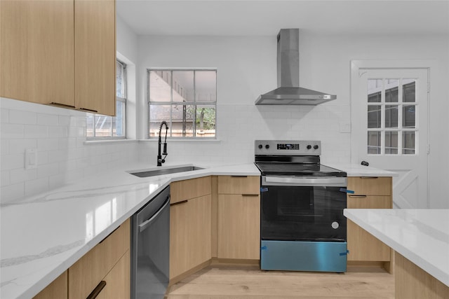 kitchen with sink, stainless steel appliances, wall chimney range hood, and light brown cabinets